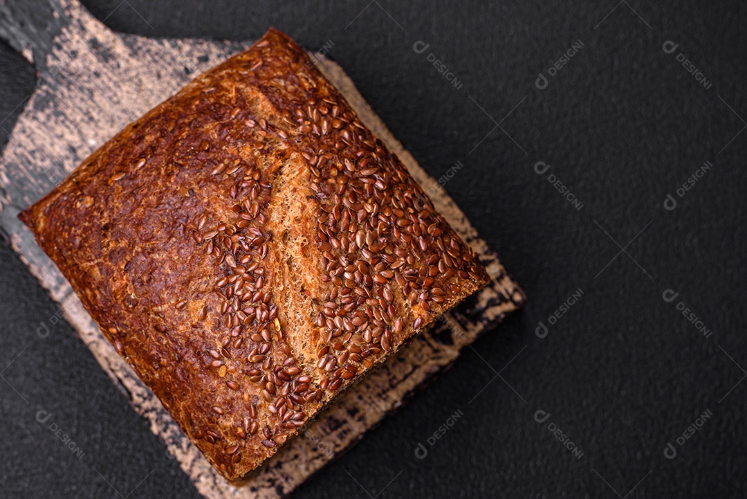 Delicioso pão integral crocante fresco com grãos e sementes sobre um fundo escuro de concreto