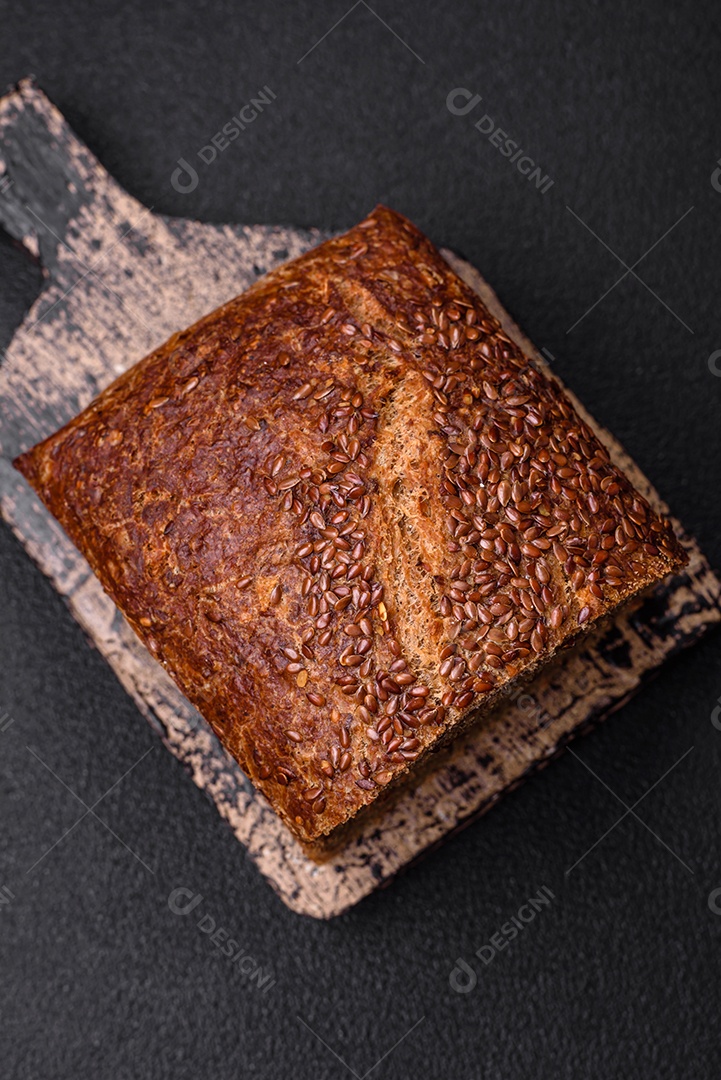 Delicioso pão integral crocante fresco com grãos e sementes sobre um fundo escuro de concreto
