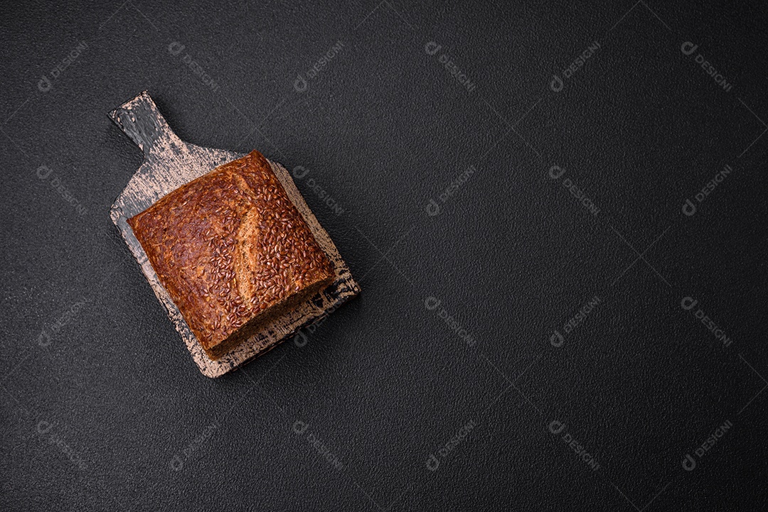 Delicioso pão integral crocante fresco com grãos e sementes sobre um fundo escuro de concreto
