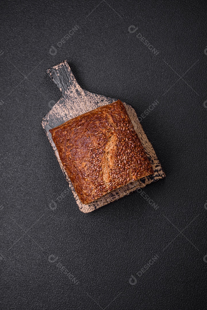 Delicioso pão integral crocante fresco com grãos e sementes sobre um fundo escuro de concreto