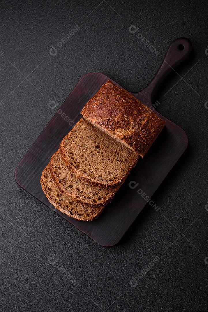 Delicioso pão integral crocante fresco com grãos e sementes sobre um fundo escuro de concreto