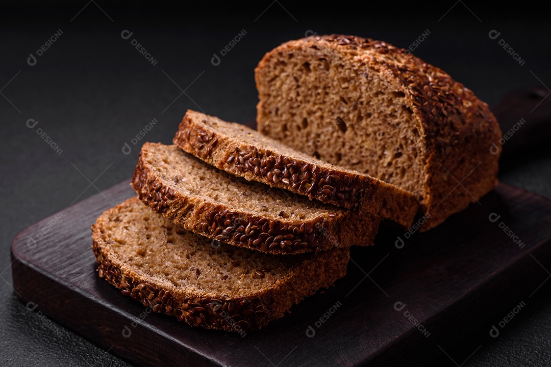 Delicioso pão integral crocante fresco com grãos e sementes sobre um fundo escuro de concreto