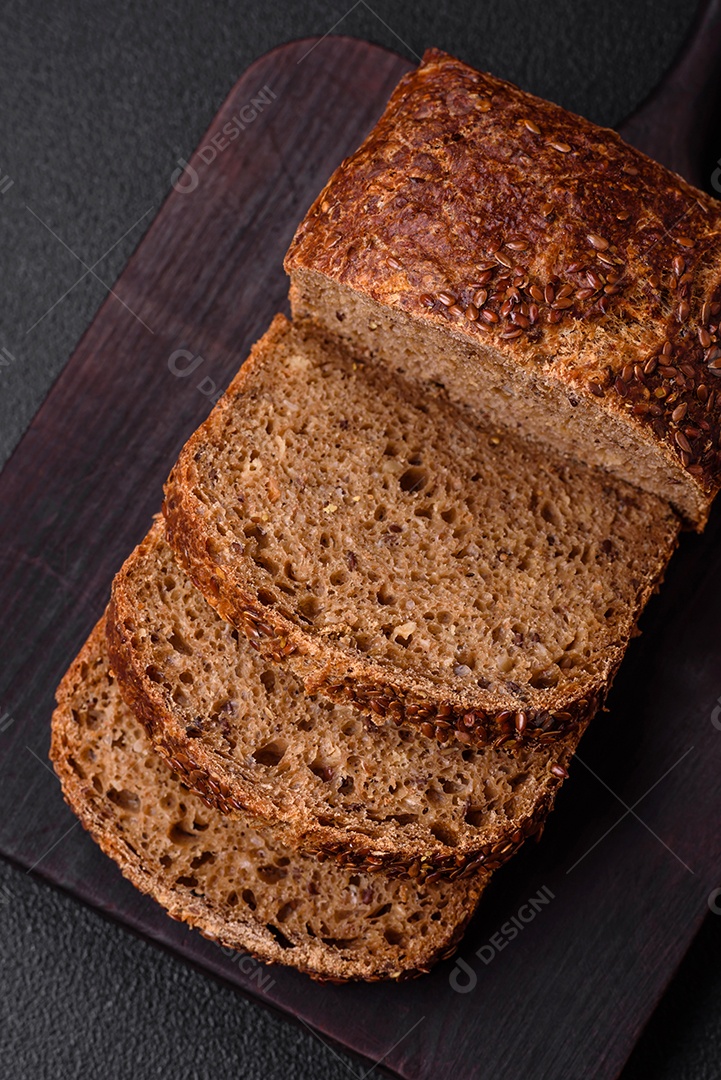 Delicioso pão integral crocante fresco com grãos e sementes sobre um fundo escuro de concreto
