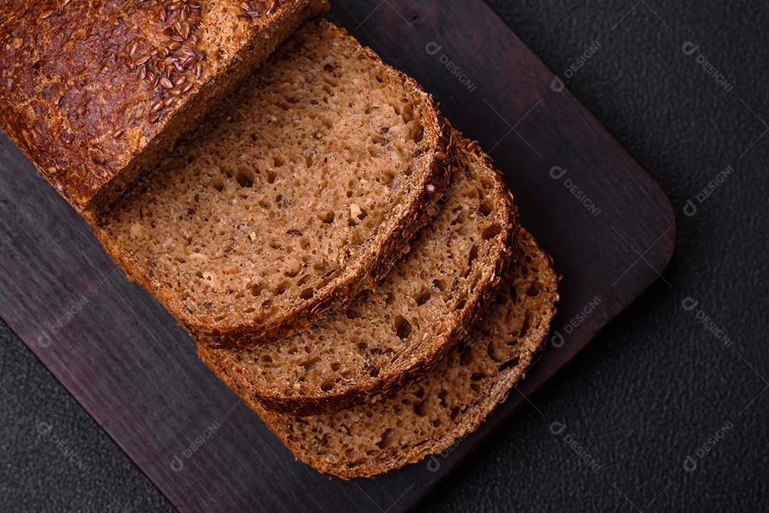 Delicioso pão integral crocante fresco com grãos e sementes sobre um fundo escuro de concreto