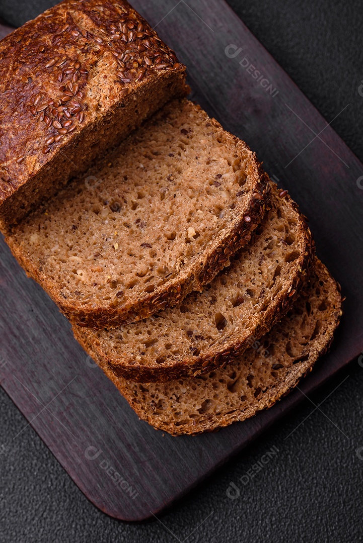 Delicioso pão integral crocante fresco com grãos e sementes sobre um fundo escuro de concreto