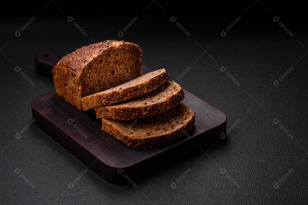 Delicioso pão integral crocante fresco com grãos e sementes sobre um fundo escuro de concreto