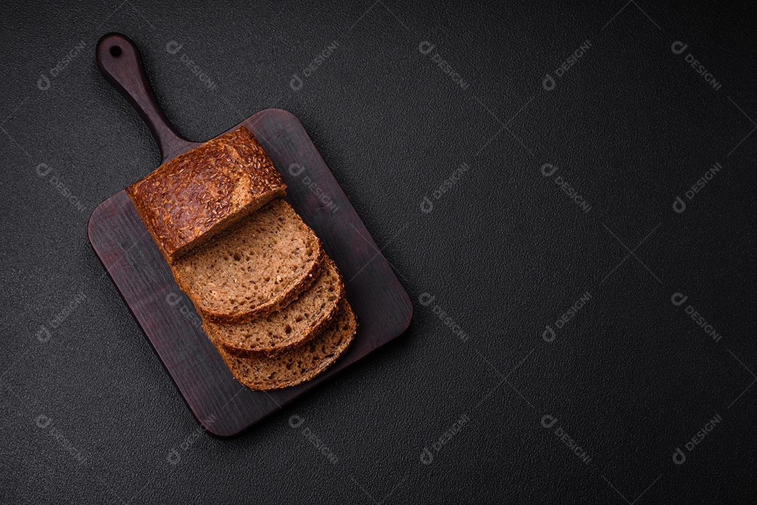 Delicioso pão integral crocante fresco com grãos e sementes sobre um fundo escuro de concreto