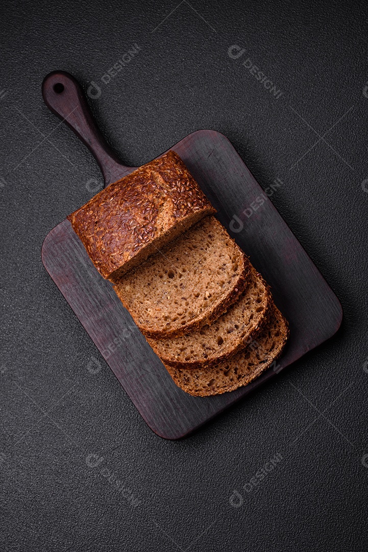 Delicioso pão integral crocante fresco com grãos e sementes sobre um fundo escuro de concreto