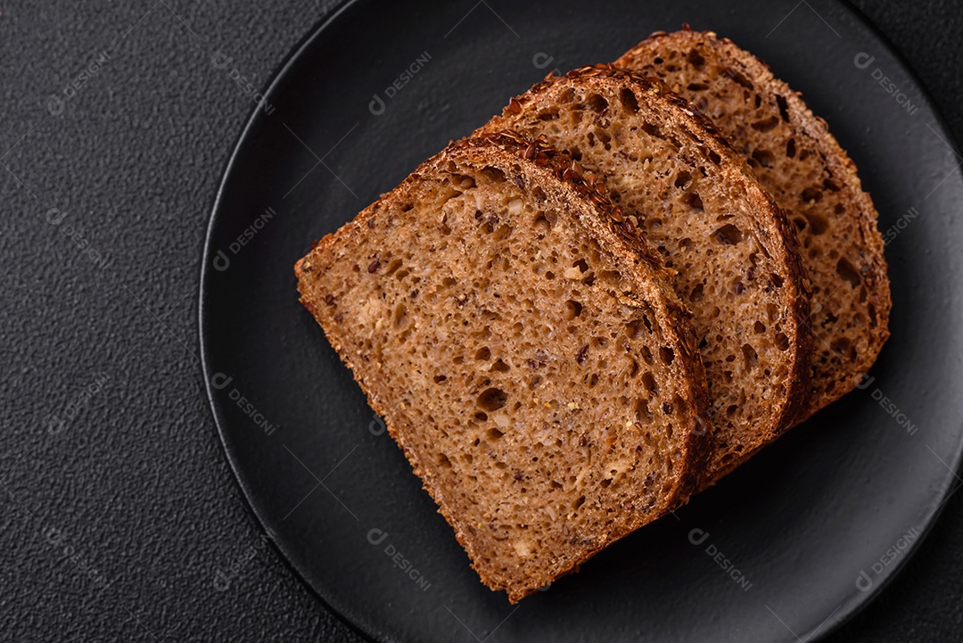 Delicioso pão integral crocante fresco com grãos e sementes sobre um fundo escuro de concreto