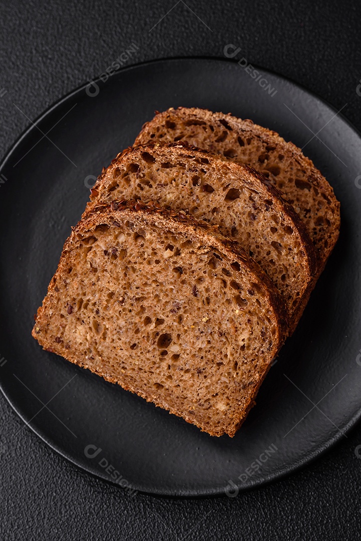 Delicioso pão integral crocante fresco com grãos e sementes sobre um fundo escuro de concreto