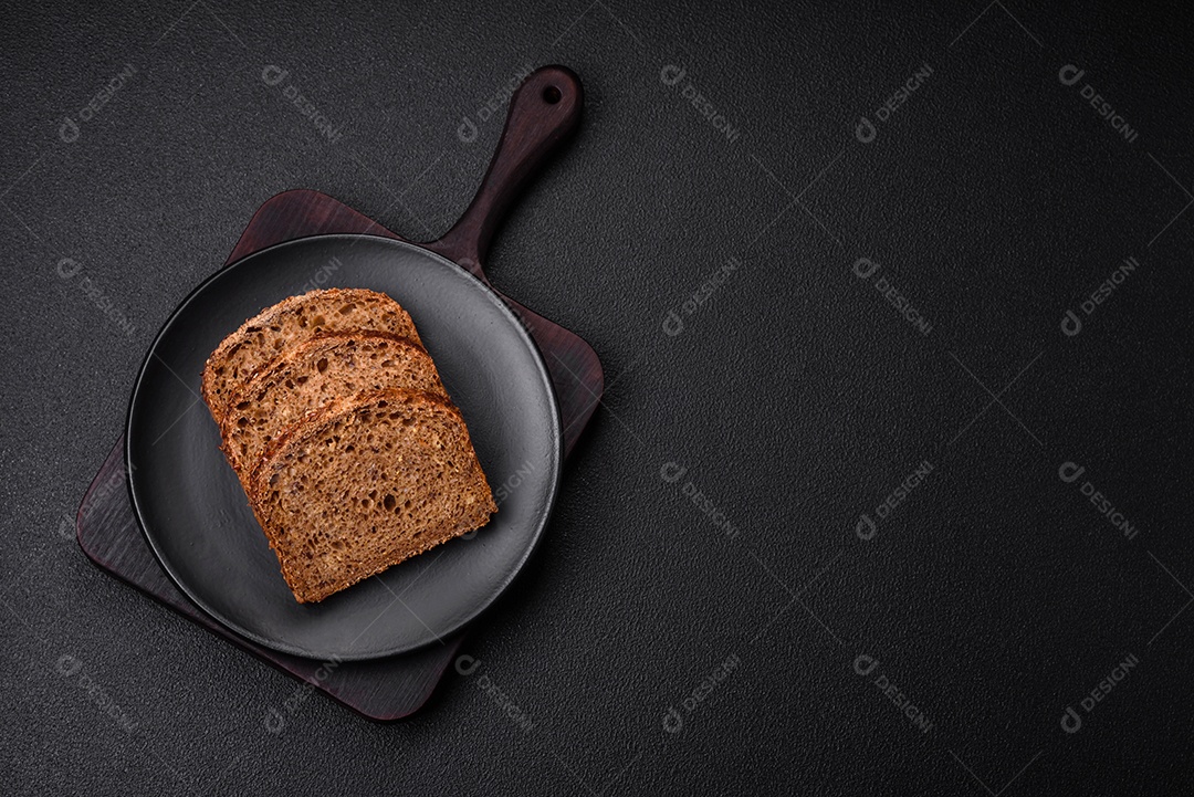 Delicioso pão integral crocante fresco com grãos e sementes sobre um fundo escuro de concreto