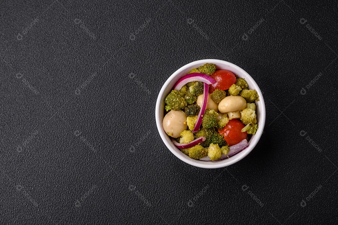 Deliciosa salada fresca de feijão verde, ervilha, pimentão e queijo com sal e especiarias sobre um fundo escuro de concreto