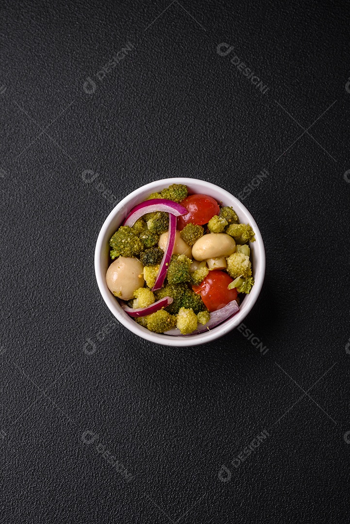 Deliciosa salada fresca de feijão verde, ervilha, pimentão e queijo com sal e especiarias sobre um fundo escuro de concreto