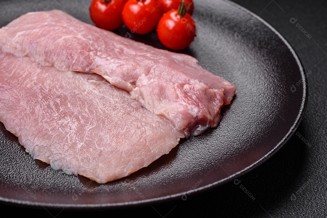 Um pedaço de carne de porco crua fresca e suculenta com sal, especiarias e ervas sobre um fundo escuro de concreto