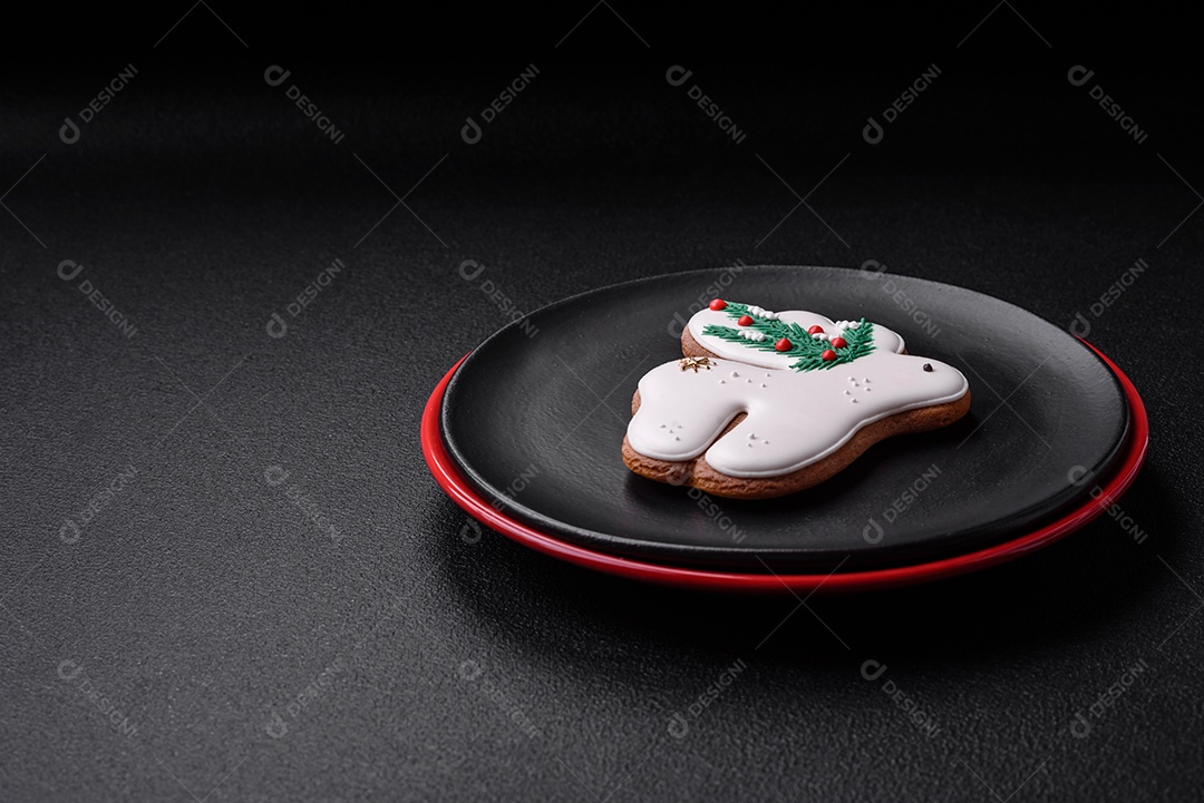 Uma bela composição de Natal composta por pratos de cerâmica, pão de gengibre e outros elementos de decoração de Ano Novo sobre um fundo escuro de concreto