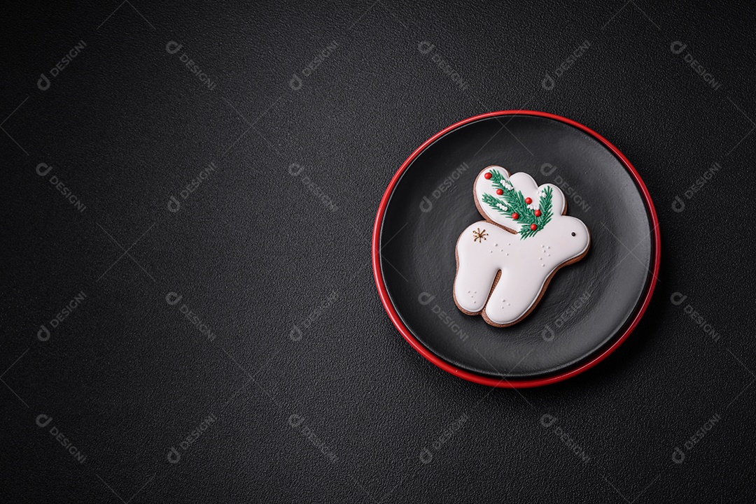 Uma bela composição de Natal composta por pratos de cerâmica, pão de gengibre e outros elementos de decoração de Ano Novo sobre um fundo escuro de concreto