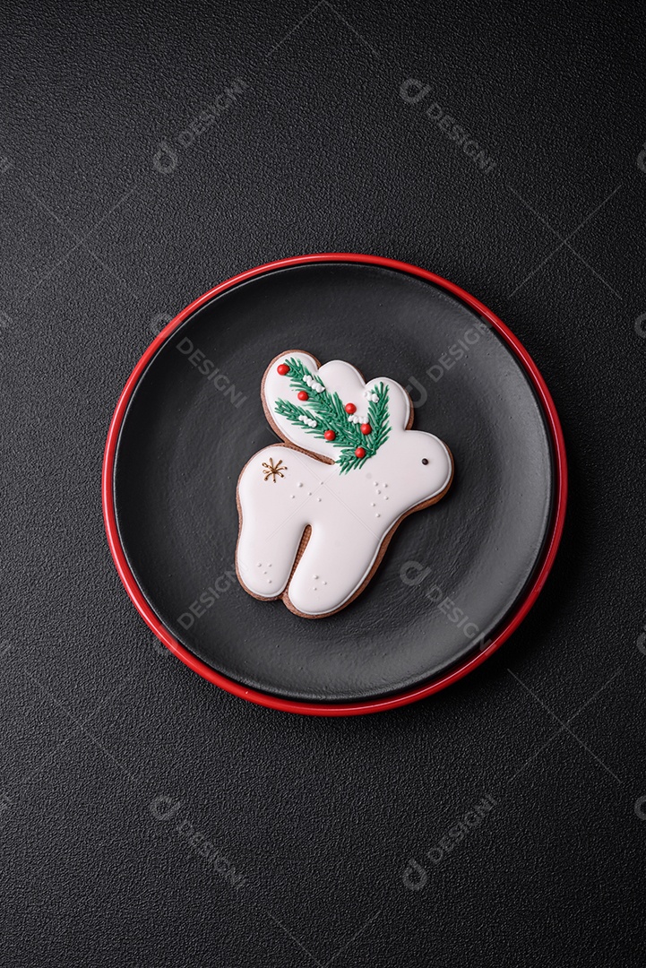 Uma bela composição de Natal composta por pratos de cerâmica, pão de gengibre e outros elementos de decoração de Ano Novo sobre um fundo escuro de concreto