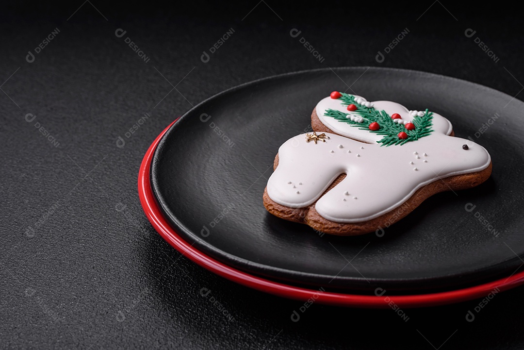 Uma bela composição de Natal composta por pratos de cerâmica, pão de gengibre e outros elementos de decoração de Ano Novo sobre um fundo escuro de concreto