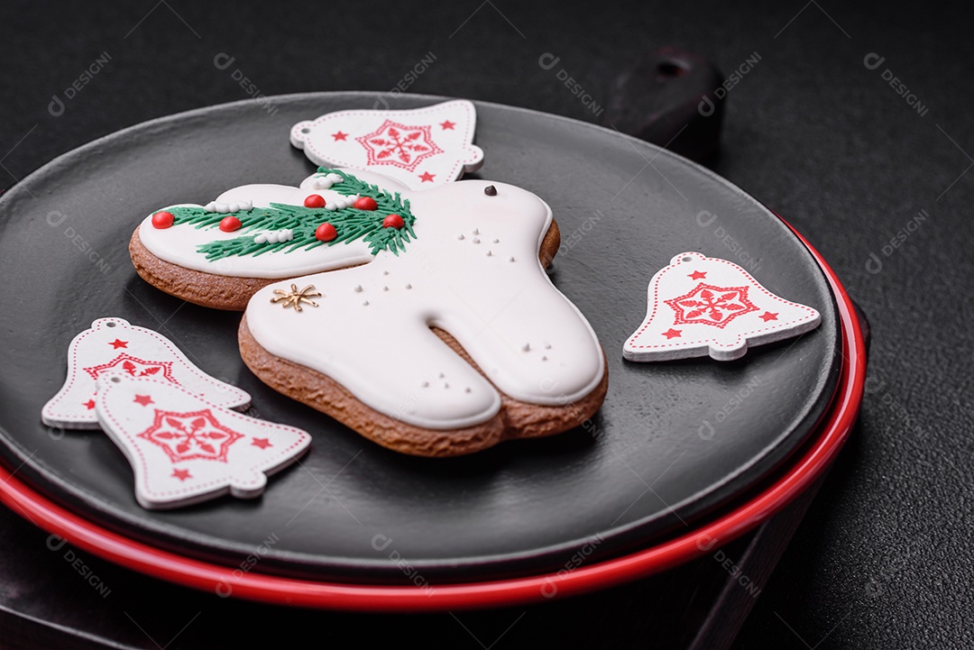 Uma bela composição de Natal composta por pratos de cerâmica, pão de gengibre e outros elementos de decoração de Ano Novo sobre um fundo escuro de concreto