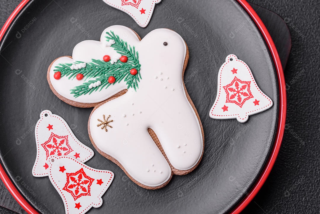 Uma bela composição de Natal composta por pratos de cerâmica, pão de gengibre e outros elementos de decoração de Ano Novo sobre um fundo escuro de concreto