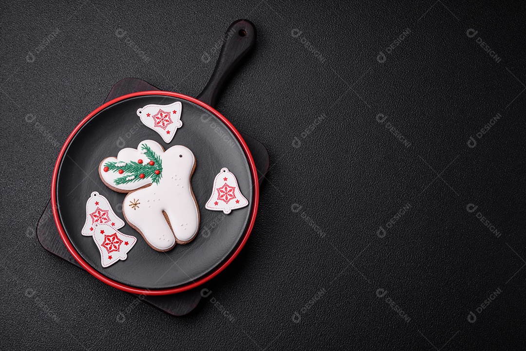 Uma bela composição de Natal composta por pratos de cerâmica, pão de gengibre e outros elementos de decoração de Ano Novo sobre um fundo escuro de concreto