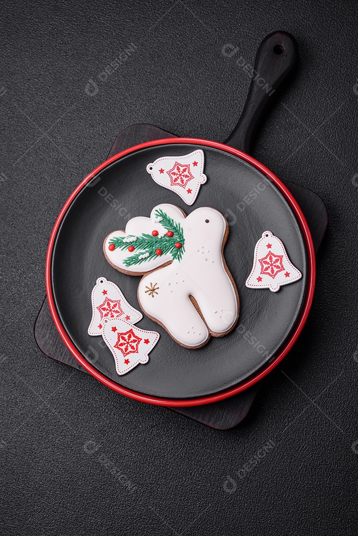 Uma bela composição de Natal composta por pratos de cerâmica, pão de gengibre e outros elementos de decoração de Ano Novo sobre um fundo escuro de concreto