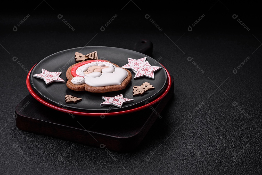 Uma bela composição de Natal composta por pratos de cerâmica, pão de gengibre e outros elementos de decoração de Ano Novo sobre um fundo escuro de concreto