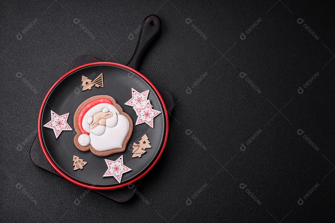 Uma bela composição de Natal composta por pratos de cerâmica, pão de gengibre e outros elementos de decoração de Ano Novo sobre um fundo escuro de concreto