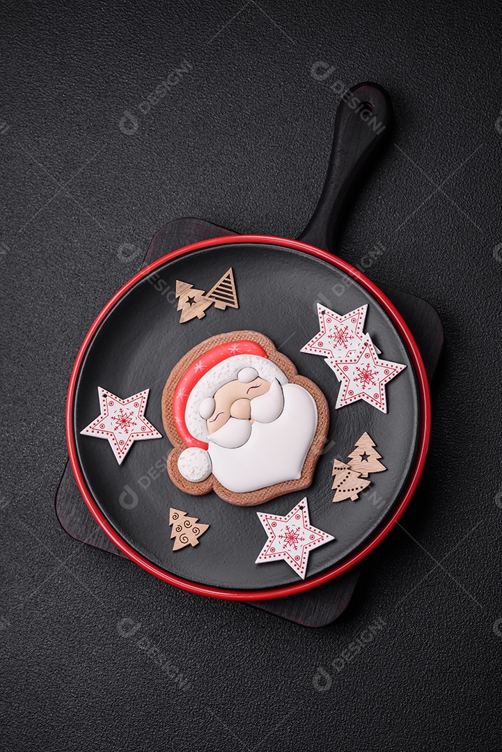 Uma bela composição de Natal composta por pratos de cerâmica, pão de gengibre e outros elementos de decoração de Ano Novo sobre um fundo escuro de concreto