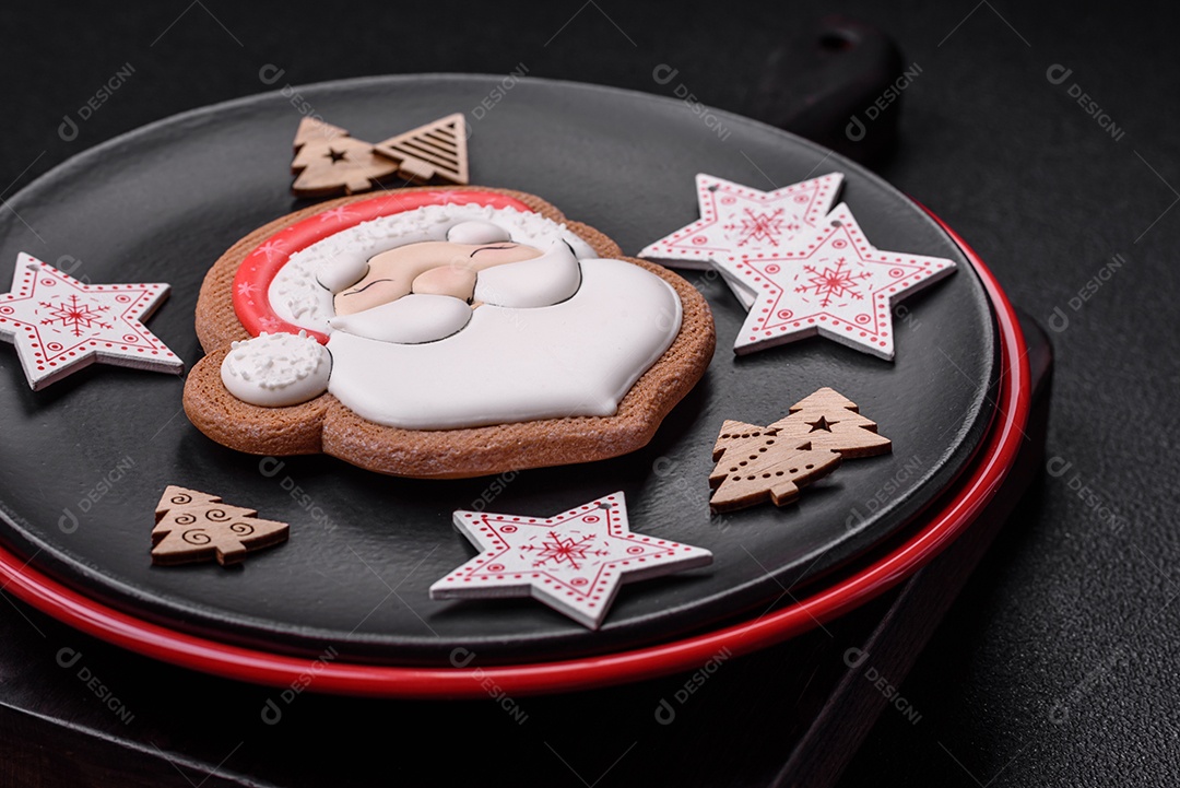 Uma bela composição de Natal composta por pratos de cerâmica, pão de gengibre e outros elementos de decoração de Ano Novo sobre um fundo escuro de concreto