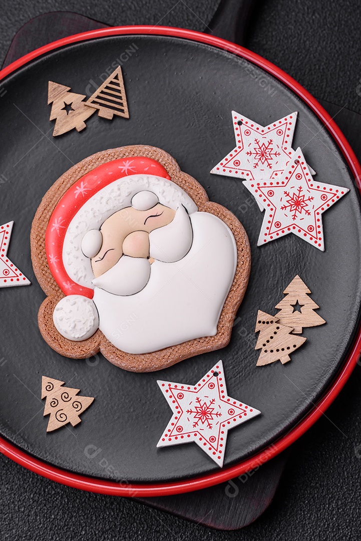 Uma bela composição de Natal composta por pratos de cerâmica, pão de gengibre e outros elementos de decoração de Ano Novo sobre um fundo escuro de concreto