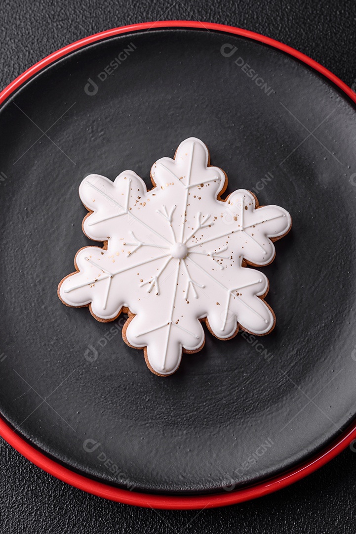 Uma bela composição de Natal composta por pratos de cerâmica, pão de gengibre e outros elementos de decoração de Ano Novo sobre um fundo escuro de concreto