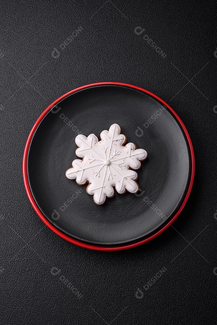 Uma bela composição de Natal composta por pratos de cerâmica, pão de gengibre e outros elementos de decoração de Ano Novo sobre um fundo escuro de concreto