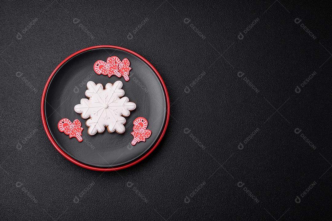 Uma bela composição de Natal composta por pratos de cerâmica, pão de gengibre e outros elementos de decoração de Ano Novo sobre um fundo escuro de concreto