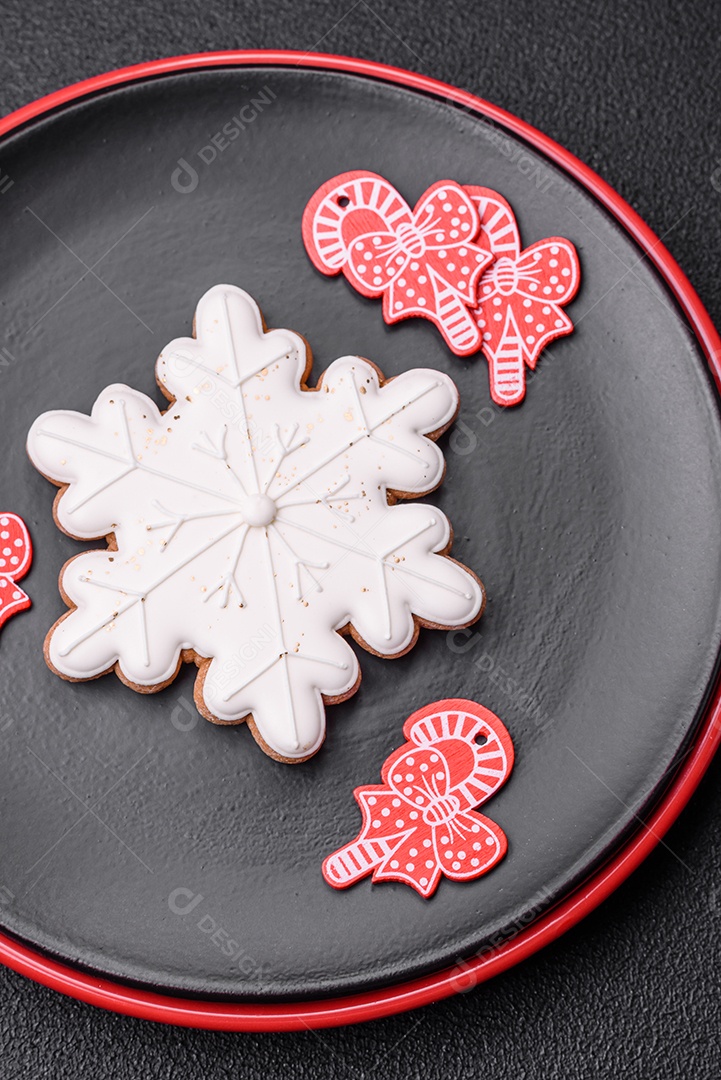 Uma bela composição de Natal composta por pratos de cerâmica, pão de gengibre e outros elementos de decoração de Ano Novo sobre um fundo escuro de concreto