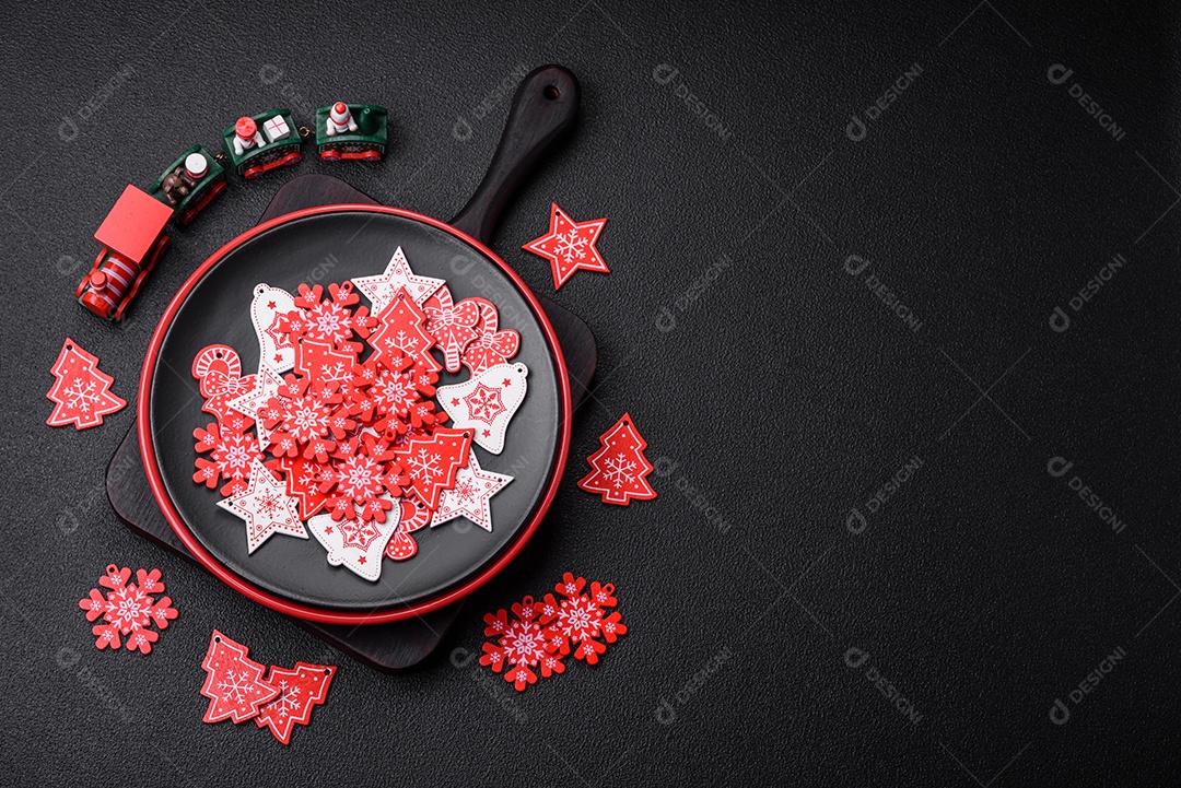 Uma bela composição de Natal composta por pratos de cerâmica, pão de gengibre e outros elementos de decoração de Ano Novo sobre um fundo escuro de concreto