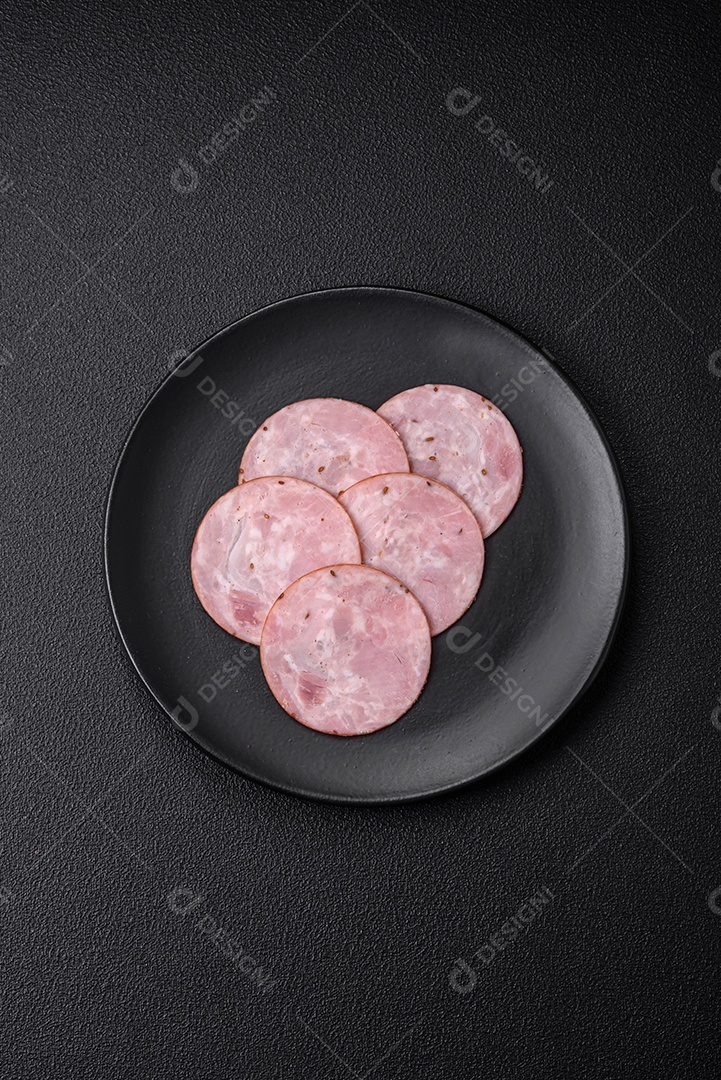 Delicioso presunto fresco cortado em fatias redondas com sal, especiarias e ervas sobre fundo escuro de concreto