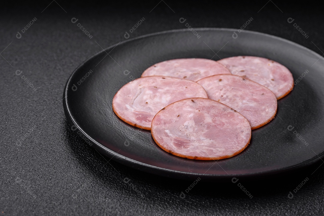 Delicioso presunto fresco cortado em fatias redondas com sal, especiarias e ervas sobre fundo escuro de concreto
