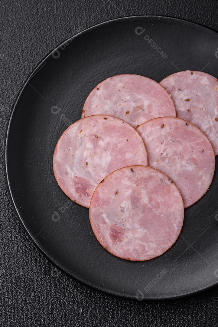 Delicioso presunto fresco cortado em fatias redondas com sal, especiarias e ervas sobre fundo escuro de concreto