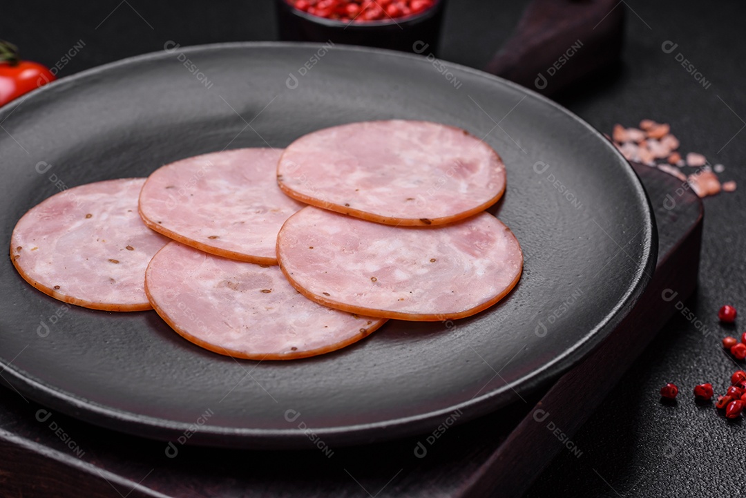 Delicioso presunto fresco cortado em fatias redondas com sal, especiarias e ervas sobre fundo escuro de concreto