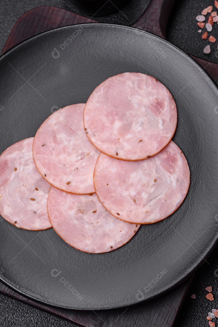 Delicioso presunto fresco cortado em fatias redondas com sal, especiarias e ervas sobre fundo escuro de concreto