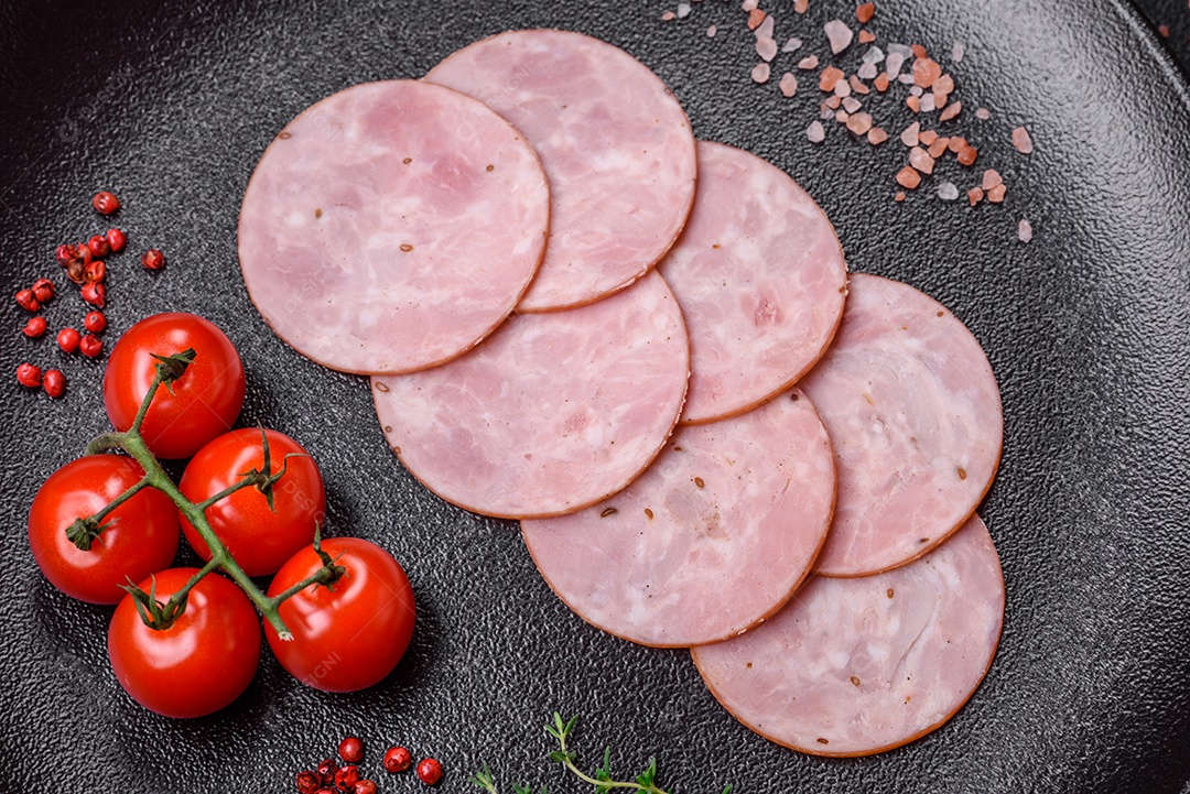 Delicioso presunto fresco cortado em fatias redondas com sal, especiarias e ervas sobre fundo escuro de concreto