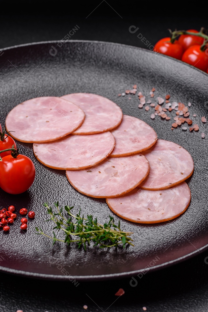 Delicioso presunto fresco cortado em fatias redondas com sal, especiarias e ervas sobre fundo escuro de concreto