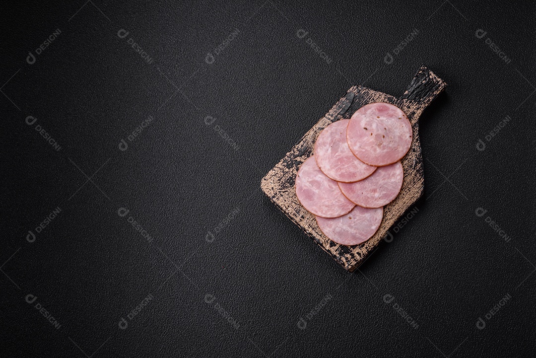 Delicioso presunto fresco cortado em fatias redondas com sal, especiarias e ervas sobre fundo escuro de concreto