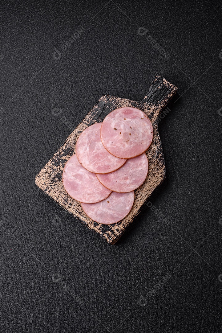 Delicioso presunto fresco cortado em fatias redondas com sal, especiarias e ervas sobre fundo escuro de concreto