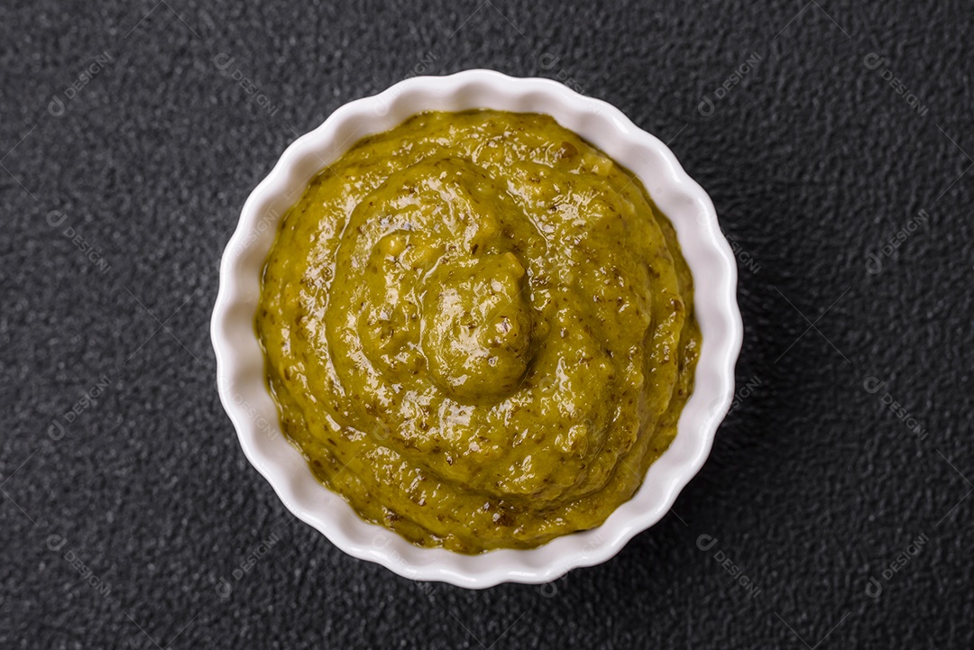 Delicioso molho vermelho picante com sal e especiarias em uma tigela de cerâmica sobre um fundo escuro de concreto