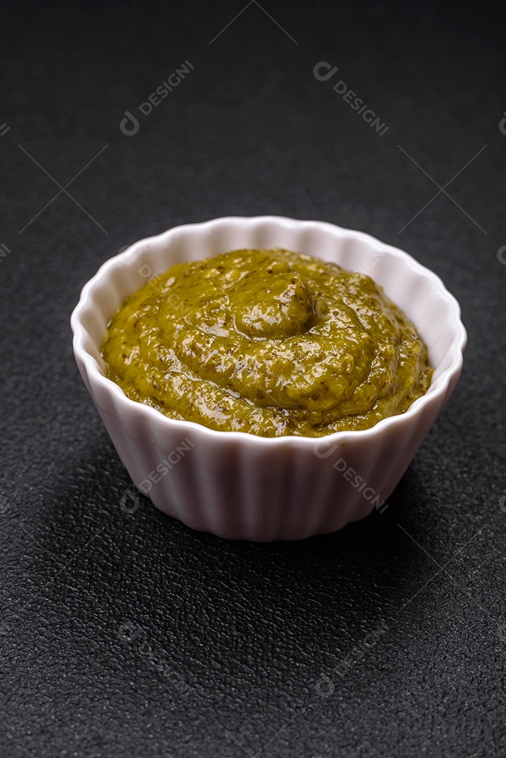 Delicioso molho vermelho picante com sal e especiarias em uma tigela de cerâmica sobre um fundo escuro de concreto