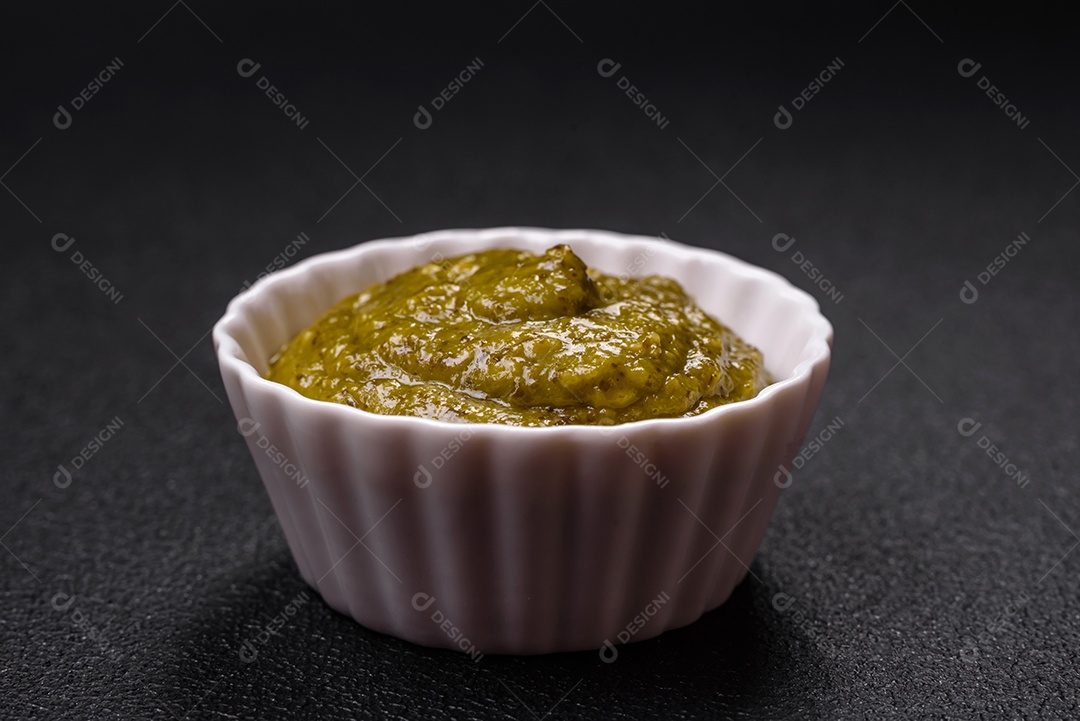 Delicioso molho vermelho picante com sal e especiarias em uma tigela de cerâmica sobre um fundo escuro de concreto