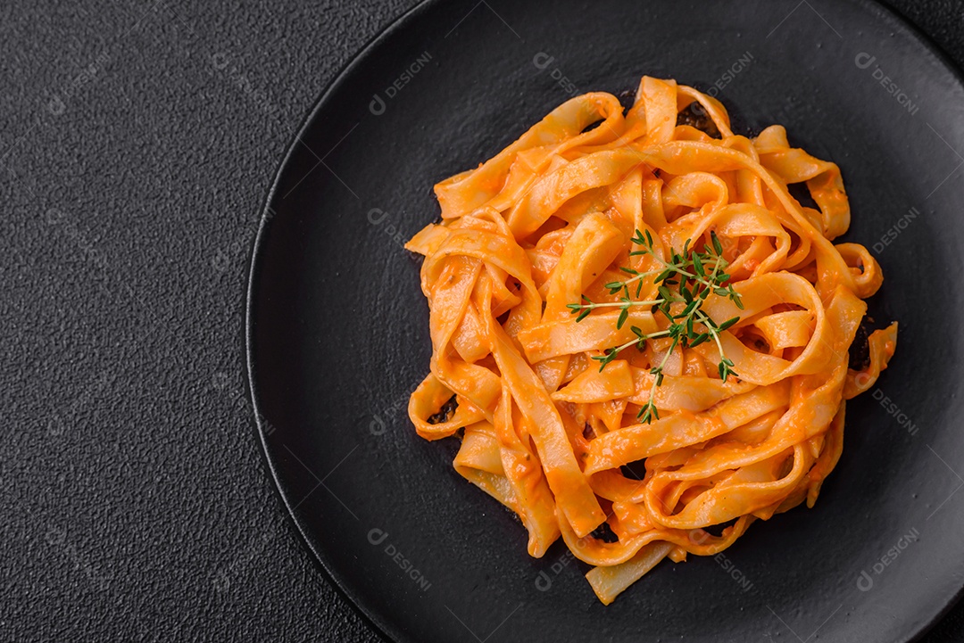 Deliciosa massa fresca com molho pesto, sal, especiarias e ervas num prato cerâmico sobre um fundo de concreto texturizado