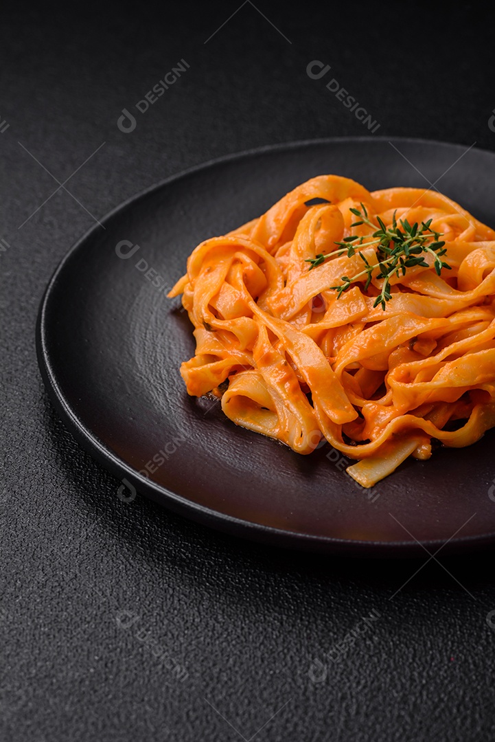 Deliciosa massa fresca com molho pesto, sal, especiarias e ervas num prato cerâmico sobre um fundo de concreto texturizado